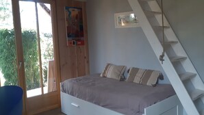 Ein Schlafzimmer mit Bett, Fenster, einer Wandregal und einer Treppe.
