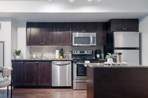 A modern kitchen with dark wood cabinets, stainless steel appliances, and a granite countertop.