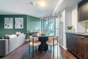 A modern kitchen with a dining area, large windows, and a view of the city. - Bright Fort York 1BR Private Balcony & Lake! (Toronto)