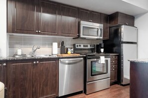 A modern kitchen with dark wood cabinets, stainless steel appliances, and a granite countertop.
