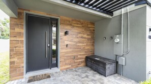 A modern exterior with a dark door, wooden wall paneling, and a utility box. - 4BR Le Reve Resort Pool Near Disney & Universal (Kissimmee)