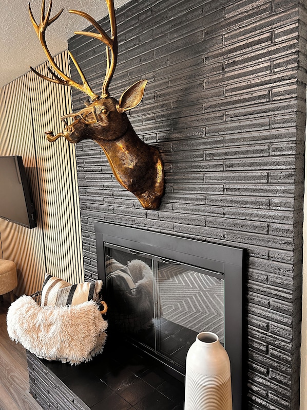A modern living room with a stone wall, a mounted deer head, a fireplace, and a framed picture.