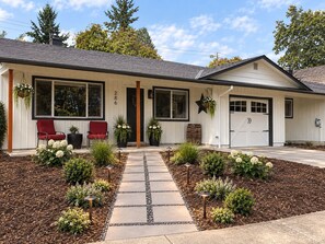 A single-story house with a front porch, a garage, and a well-maintained garden.