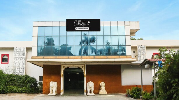 Un edificio con fachada de vidrio que refleja árboles y un letrero que dice 'Collection Company-Serviced'.