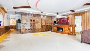 Una zona de recepción con mostrador de madera, un reloj y un separador decorativo.