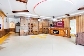 A reception area with a wooden reception desk, a clock, and a decorative partition. - Collection O Bhiwadi (Bhiwadi)