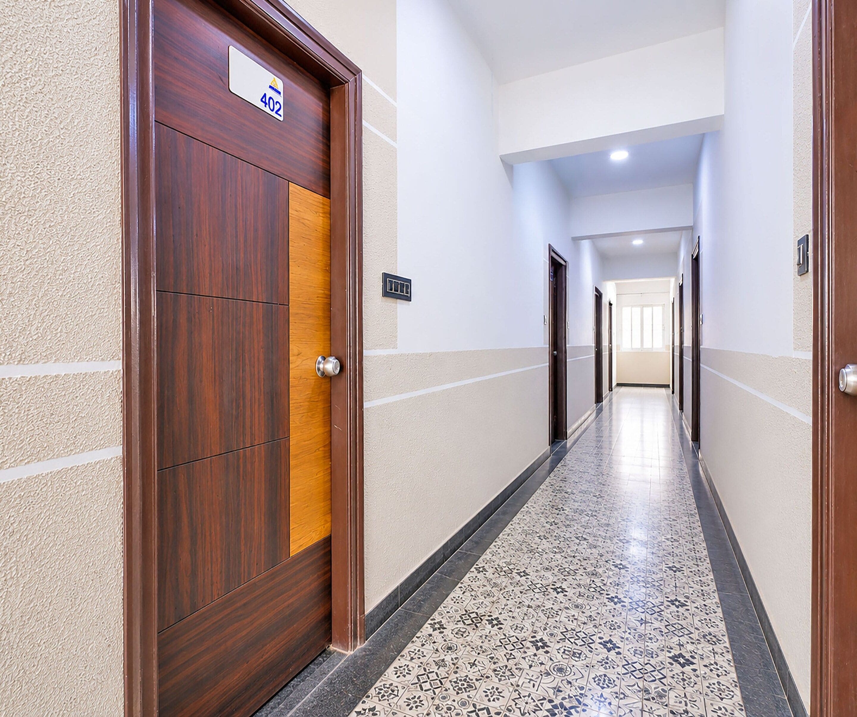 A hotel corridor with a wooden door marked '402' and a tiled floor.