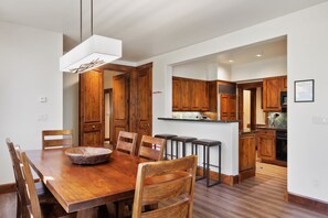 A modern kitchen with wooden cabinets, a central island, and a dining area with a large wooden table and chairs. - Outpost: Grand View 3220 - Has A/C! (Jackson)