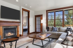 A living room with a fireplace, a sofa, a coffee table, and a television. - Outpost: Grand View 3220 - Has A/C! (Jackson)