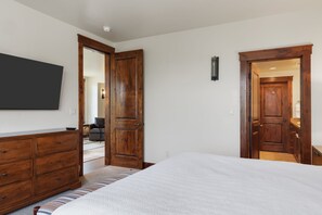 Ein Schlafzimmer mit einem Bett, einer Holzkommode und einem an der Wand befestigten Fernseher.
