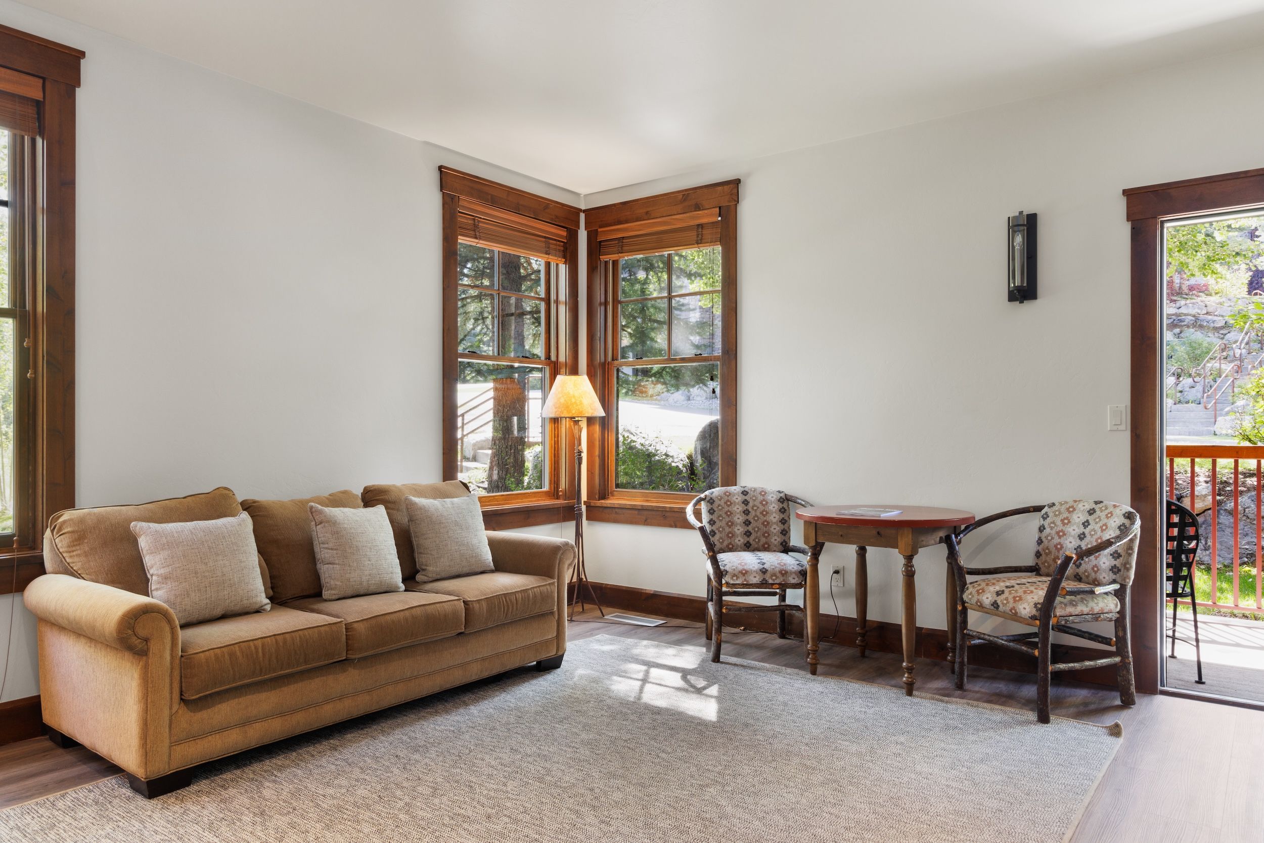 A cozy living room with a sofa, chairs, a table, and large windows.
