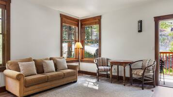 A cozy living room with a sofa, chairs, a table, and large windows.