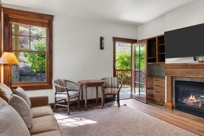 A cozy living room with a fireplace, a sofa, a table with chairs, and a TV mounted on the wall. - Outpost: Grand View 322s - Has A/C (Jackson)