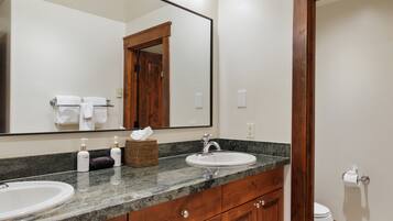 A bathroom with a large mirror, two sinks, a wooden vanity, and a toilet.
