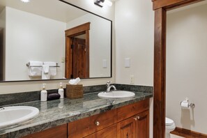 A bathroom with a large mirror, two sinks, a wooden vanity, and a toilet. - Outpost: Grand View 322s - Has A/C (Jackson)