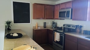 Una cocina con gabinetes de madera, microondas, estufa y cafetera.
