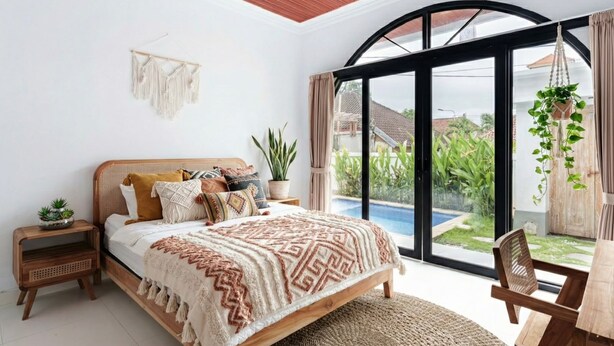 A bedroom with a bed, bedside tables, a window, and a view of a swimming pool. - Aesthetic 3BR Bohemian Villa with Private Pool in Batu Bolong,Central Canggu (Badung)