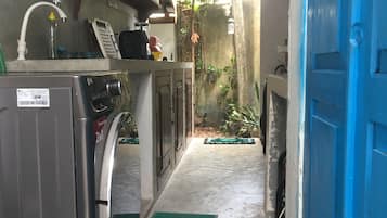 A narrow corridor with a washing machine, a blue door, and a concrete floor.