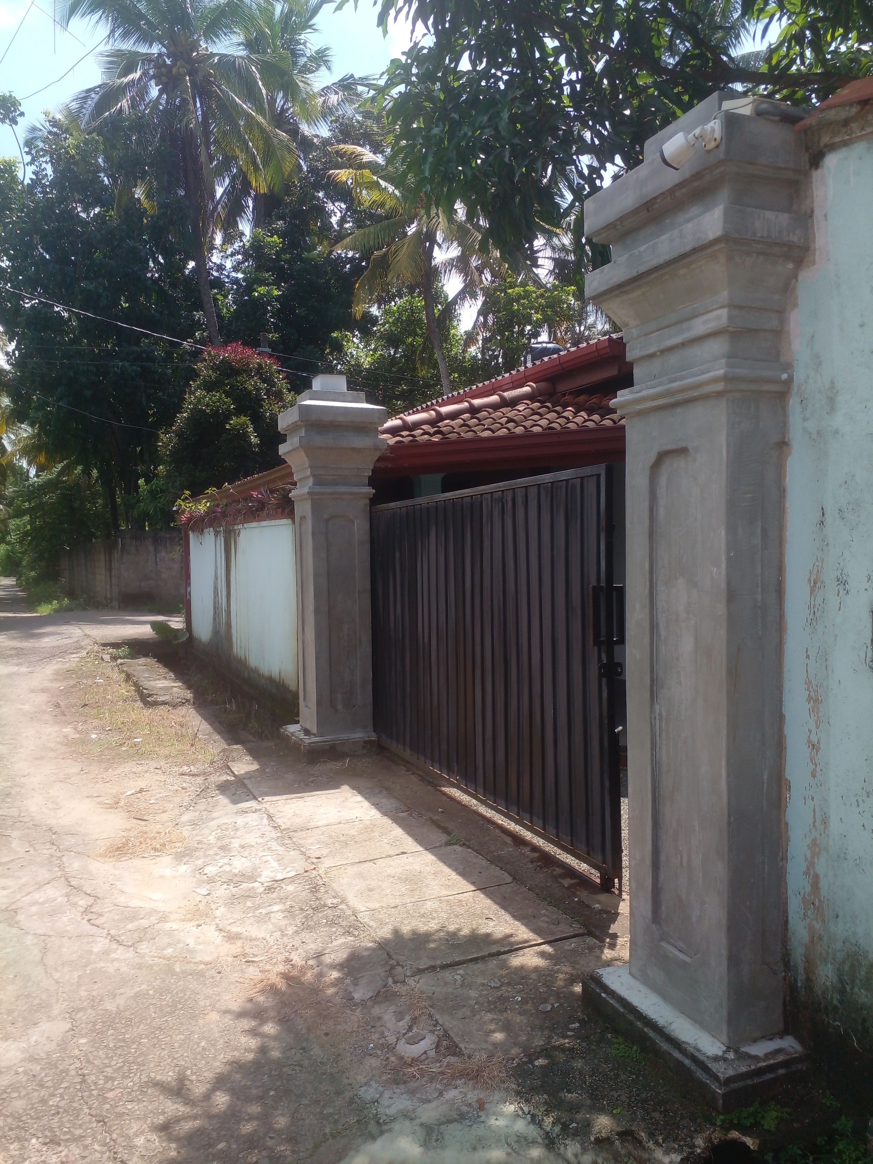 A gated property with a concrete wall, a metal gate, and a tiled roof.
