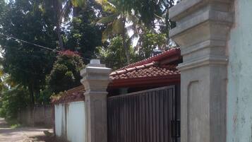 A gated property with a concrete wall, a metal gate, and a tiled roof.
