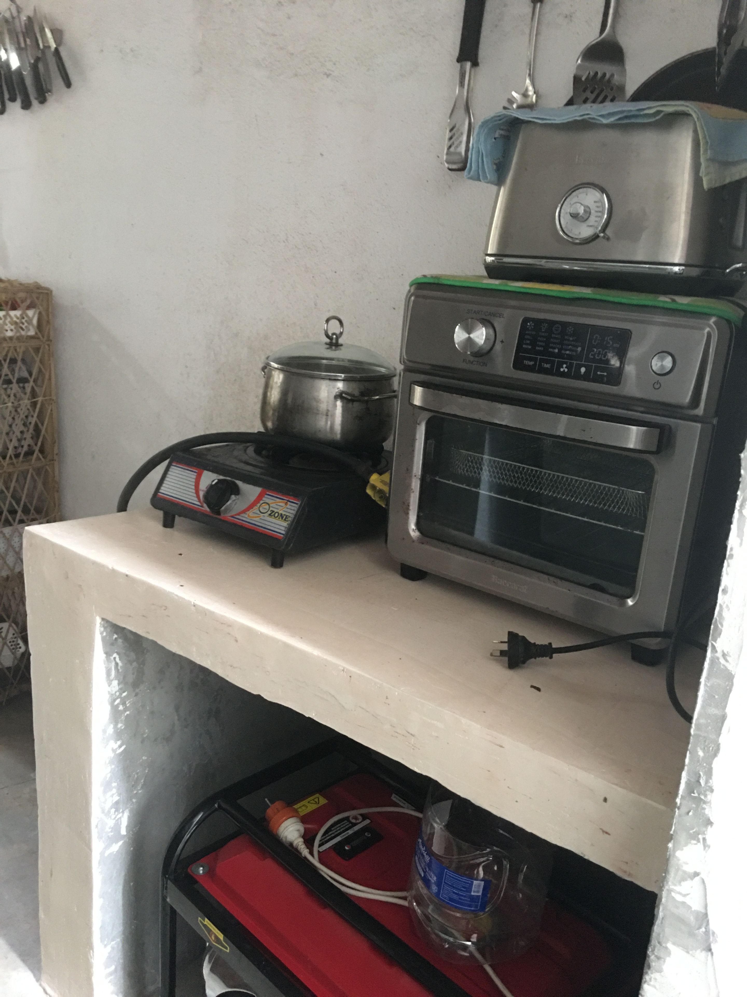 Une petite cuisine équipée d’une cuisinière, d’un four et d’une casserole posée sur le plan de travail.