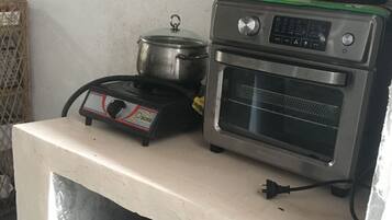 Une petite cuisine équipée d’une cuisinière, d’un four et d’une casserole posée sur le plan de travail.