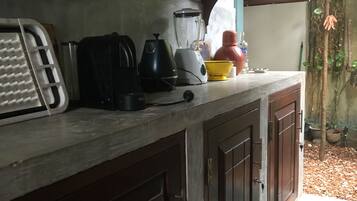 Een keuken met een aanrecht, een broodrooster, een blender, een waterkoker en diverse potjes en bakken.