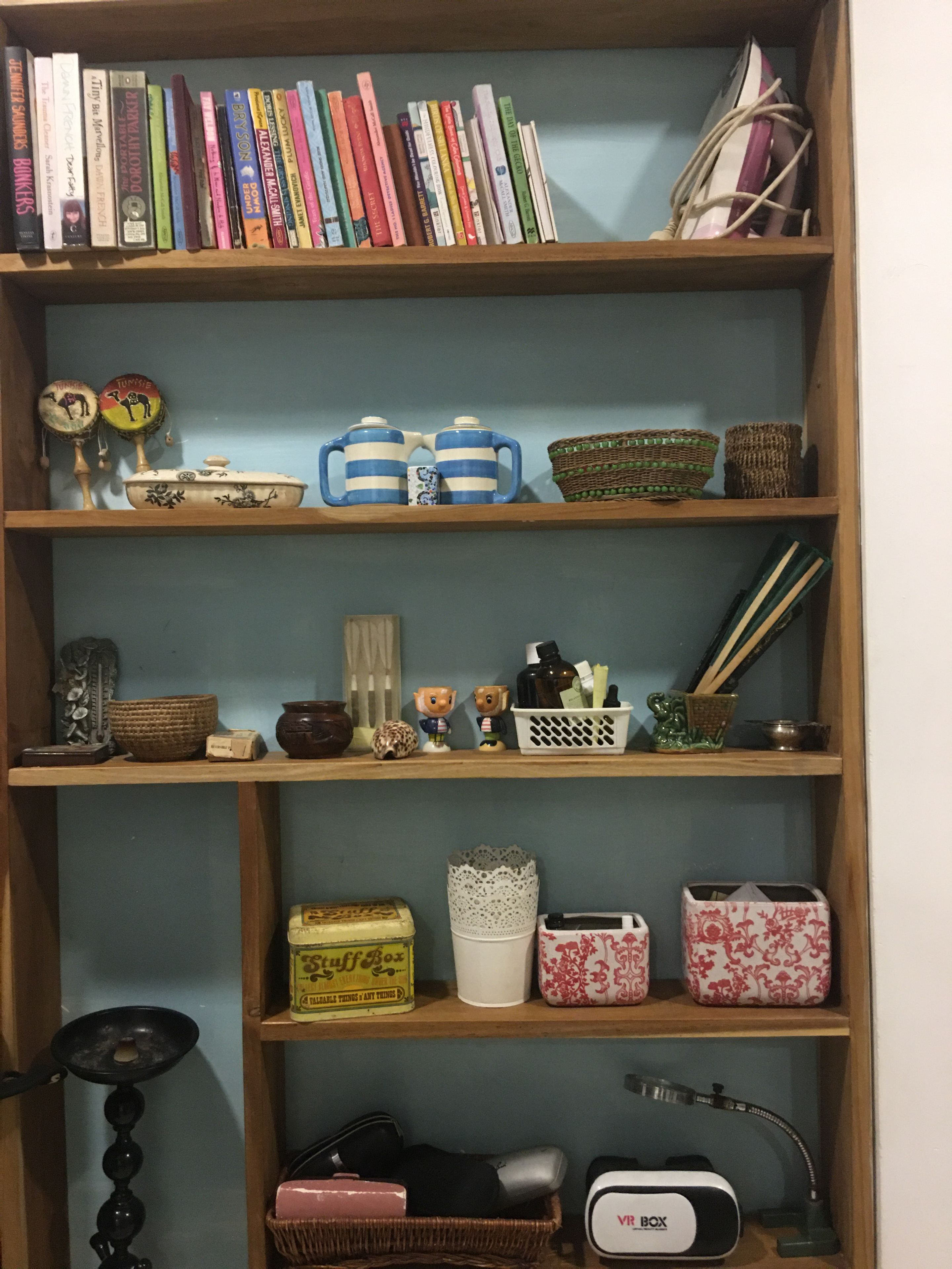 Une bibliothèque contenant divers livres, des objets de décoration et des boîtes de rangement.