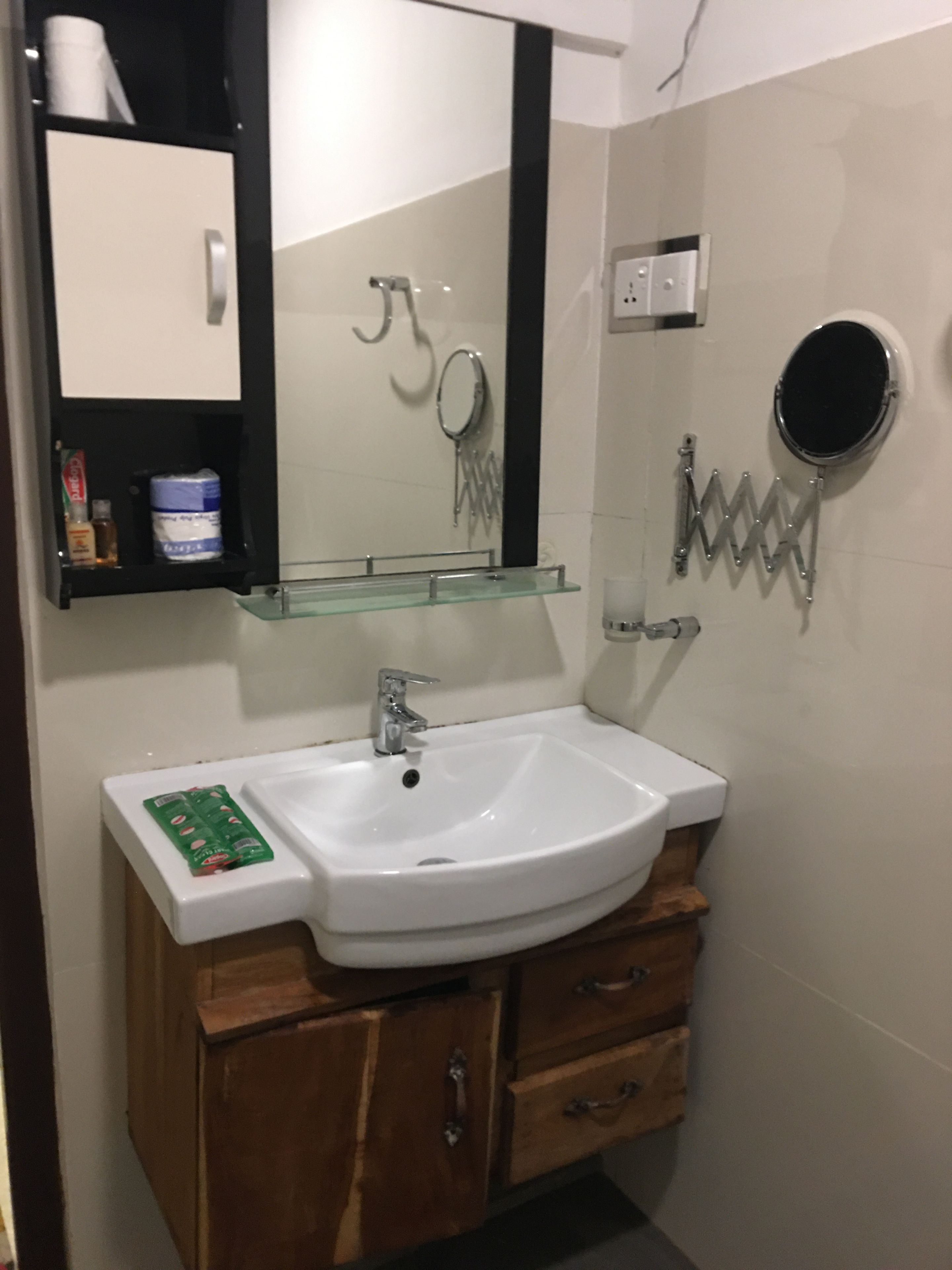 A bathroom with a white sink, wooden vanity, a mirror, and a towel rack.