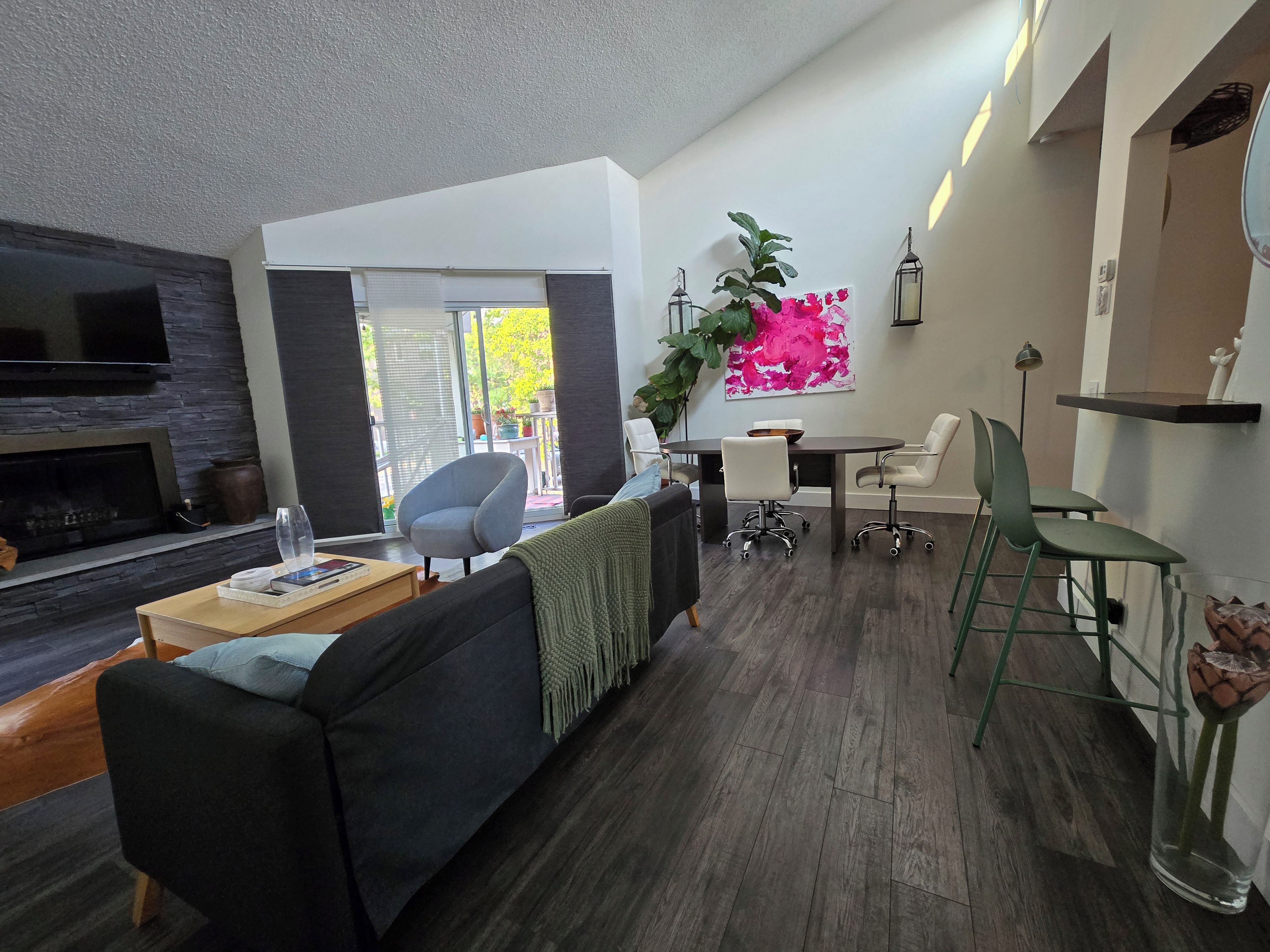A modern living room with a fireplace, a dining area with a table and chairs, and a large window with a view.