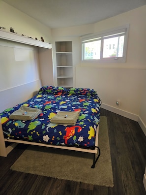 A bedroom with a bed, a window, and a built-in shelf.