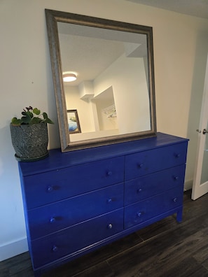 A blue dresser with a mirror and a potted plant.