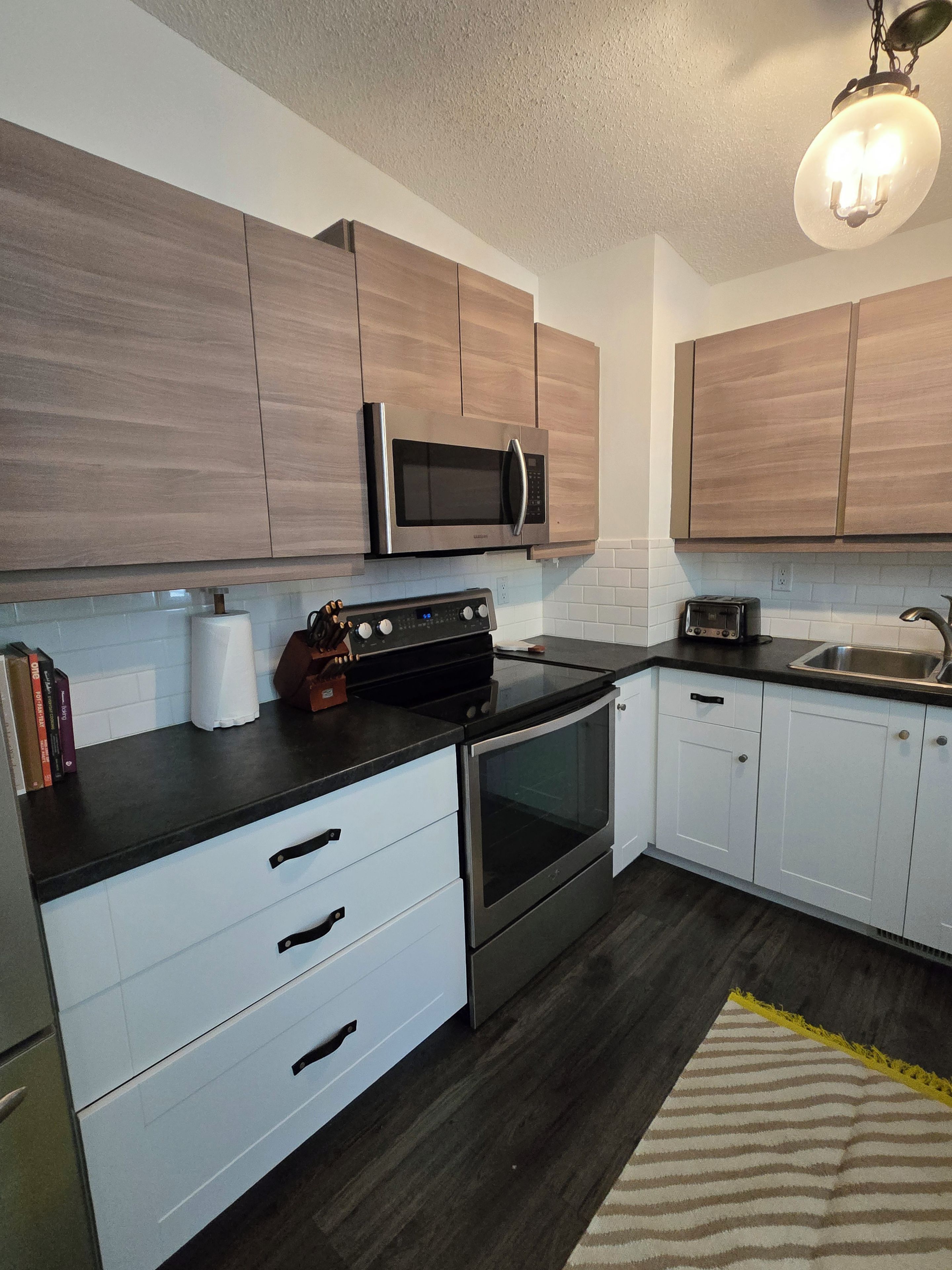 A modern kitchen with wooden cabinets, a built-in microwave, a stove, and a dishwasher.