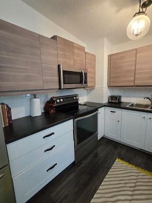 A modern kitchen with wooden cabinets, a built-in microwave, a stove, and a dishwasher.