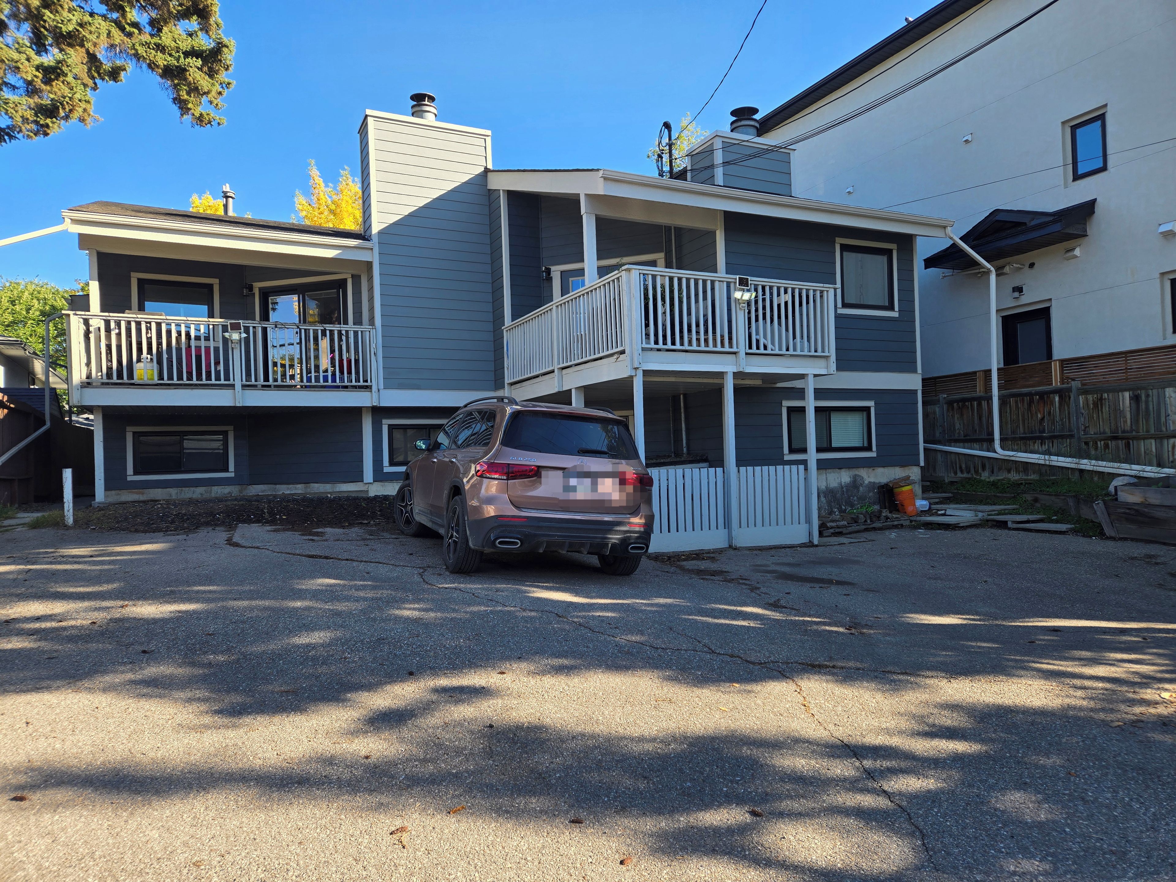 A two-story residential building with a car parked in front.