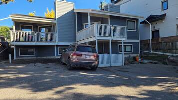 A two-story residential building with a car parked in front.