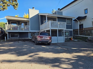 A two-story residential building with a car parked in front.