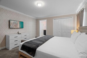 A bedroom with a bed, a dresser, a painting, and a door. - 4BD/3BA Family Escape | Private Pool near Disney (Davenport)