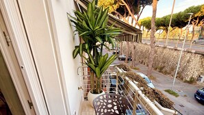 Un balcon avec une table ronde, un pot de fleurs et une vue sur la rue.