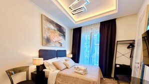 Une chambre d’hôtel avec un lit, une chaise, un bureau, une lampe, un tableau et une vue sur l’extérieur.