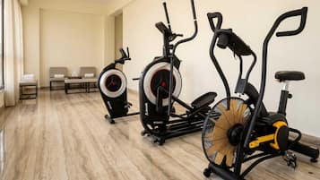 A gym with three stationary bikes, a bench, and a mirror.