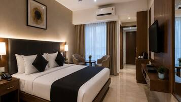 A hotel room with a bed, bedside lamps, a ceiling fan, an air conditioning unit, a television, and a small table with a plant.
