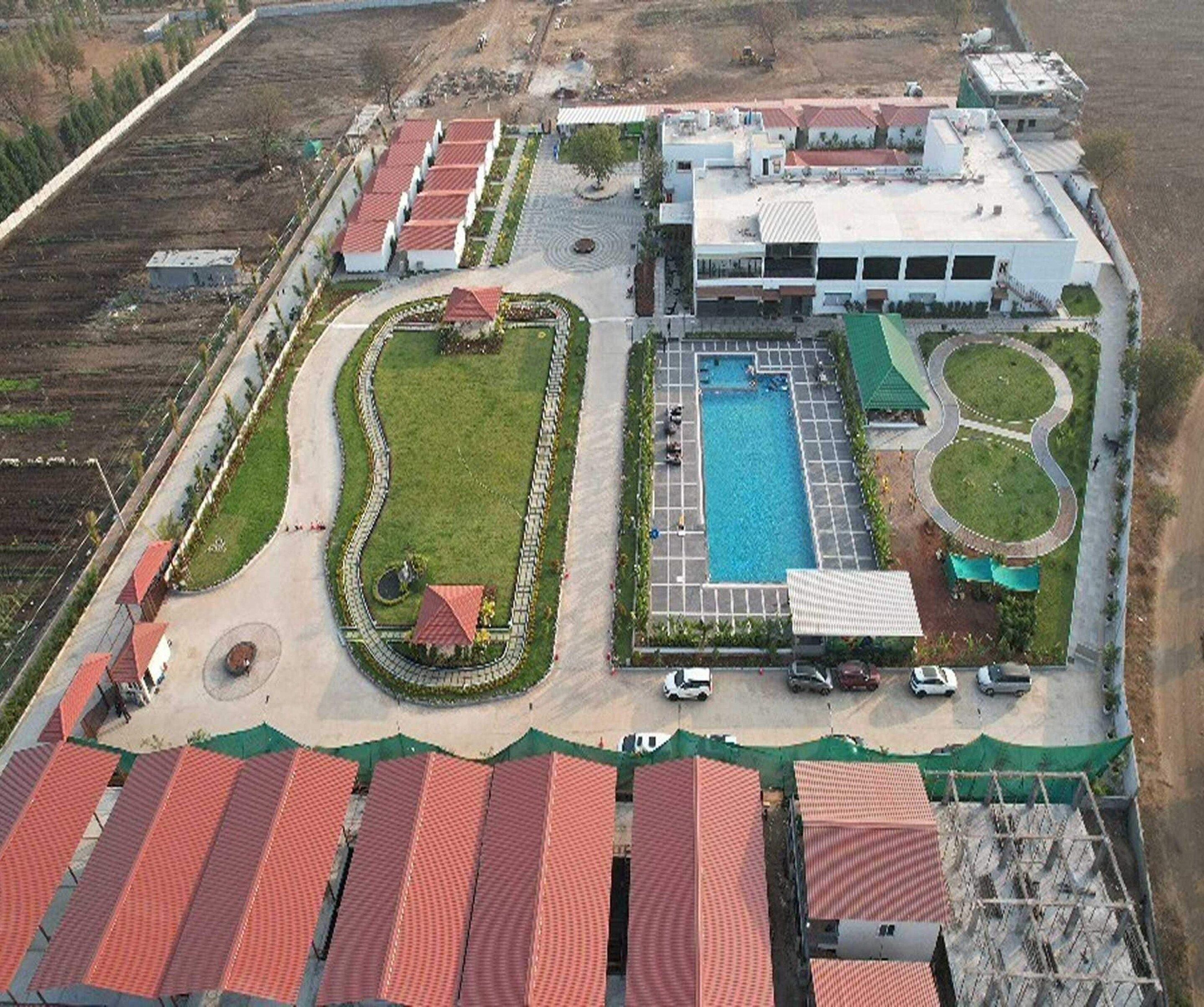 Luchtbeeld van een hotel met een zwembad, meerdere gebouwen en een aangelegde tuin.
