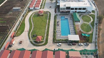 An aerial view of a hotel with a swimming pool, multiple buildings, and a landscaped garden.