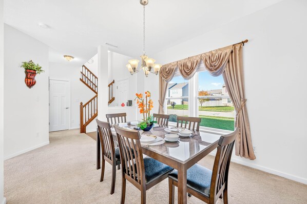A dining area with a wooden table, chairs, and a chandelier.