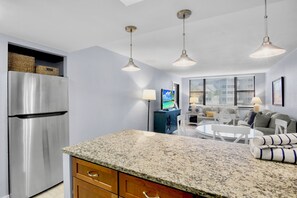Una cocina moderna con encimeras de granito, un refrigerador de acero inoxidable e iluminación colgante.
