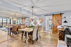 Un comedor moderno con sillas de mimbre, una mesa de madera e iluminación colgante.