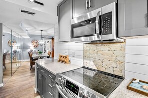 Una cocina moderna con microondas integrado, estufa y encimeras de granito.