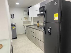 A modern kitchen with a black refrigerator, a microwave, and a gas stove. - Aves María 6th Floor With Balcony and Parking (Sabaneta)