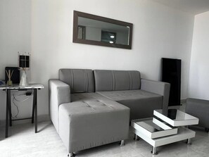 A modern living room with a grey sofa, a coffee table, and a TV stand. - Aves María 6th Floor With Balcony and Parking (Sabaneta)